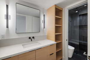 Full bath with tiled shower, vanity, and built in shelves