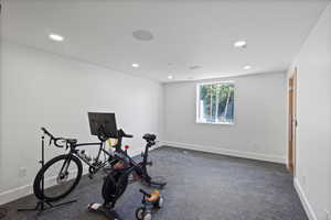Exercise room with dark colored carpet and recessed lighting