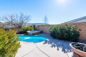 View of swimming pool featuring a fenced backyard, patio surround, and an in-ground hot tub