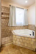 Bathroom with a garden tub and tile patterned flooring
