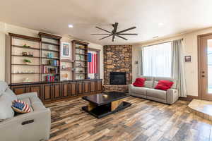 Living area with wood finished floors, a ceiling fan, a fireplace, and recessed lighting