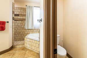 Full bathroom featuring a garden tub, light tile patterned floors, and a tile shower