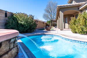 View of swimming pool with patio surround and a fenced backyard