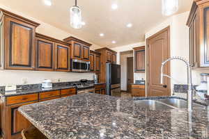 Kitchen featuring pendant lighting, stainless steel appliances, a peninsula, and dark stone counters