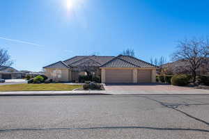 View of front of house featuring stucco siding, concrete driveway, a tile roof, and a garage