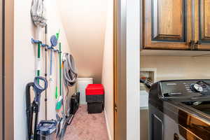 Laundry room with washer / clothes dryer, light colored carpet, and cabinet space