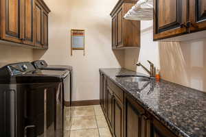 Laundry room with washer and clothes dryer, cabinet space, and light tile patterned floors