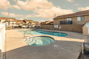 Community pool with a patio area, a residential view, and a hot tub