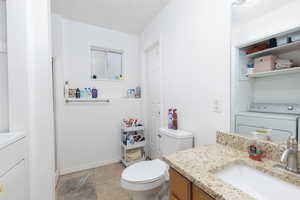 Full bath featuring vanity, washer / dryer, and light tile patterned flooring