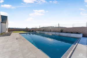 View of swimming pool featuring patio surround and a fenced backyard