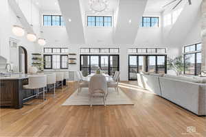 Dining area featuring light wood-style flooring, recessed lighting, and a high ceiling