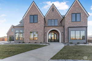 View of front of property featuring brick siding, a front lawn, and french doors
