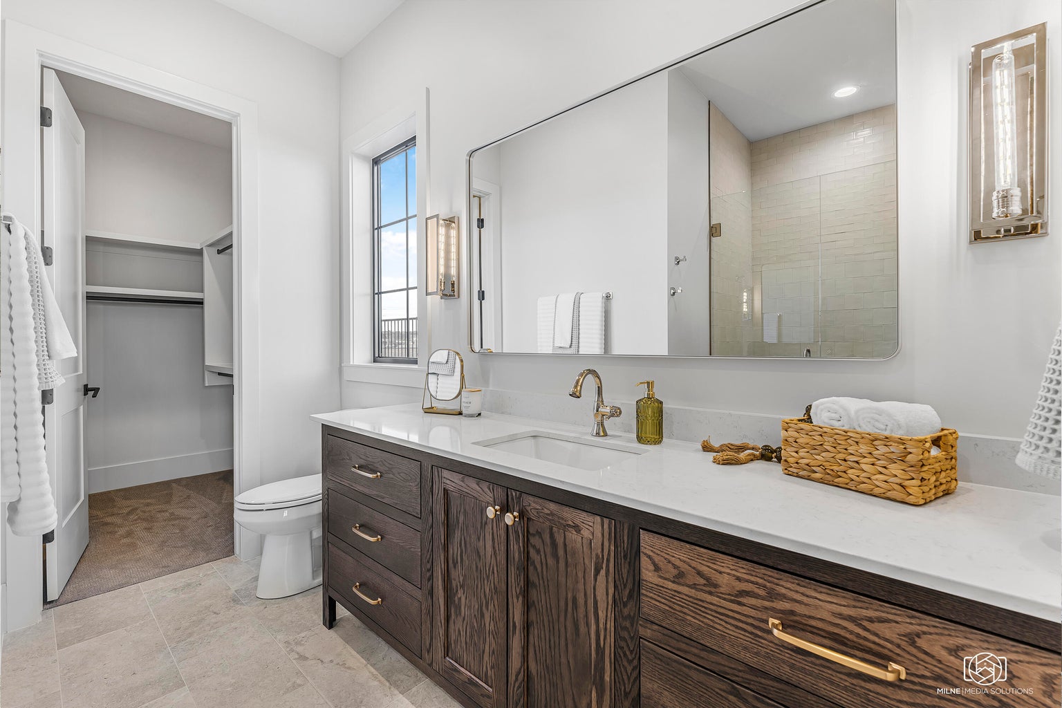 Bathroom featuring a shower stall, vanity, and a spacious closet