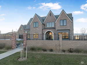 View of front of property with brick siding, a fenced front yard, and a standing seam roof