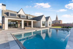 Rear view of property featuring a patio area, a standing seam roof, stucco siding, and brick siding