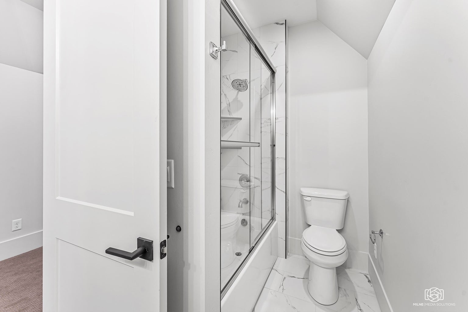 Bathroom featuring combined bath / shower with glass door, vaulted ceiling, and light marble finish floors