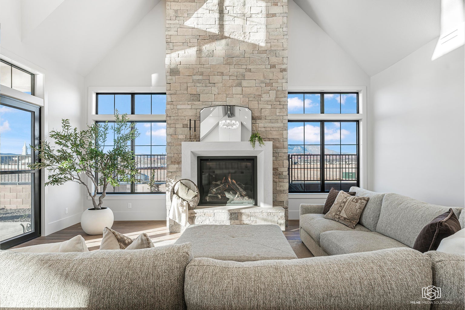 Living room featuring a glass covered fireplace, wood finished floors, and lofted ceiling