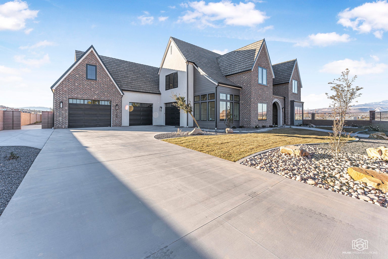 View of front of property featuring brick siding, concrete driveway, and a chimney