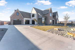 View of front of property featuring brick siding, concrete driveway, and a chimney
