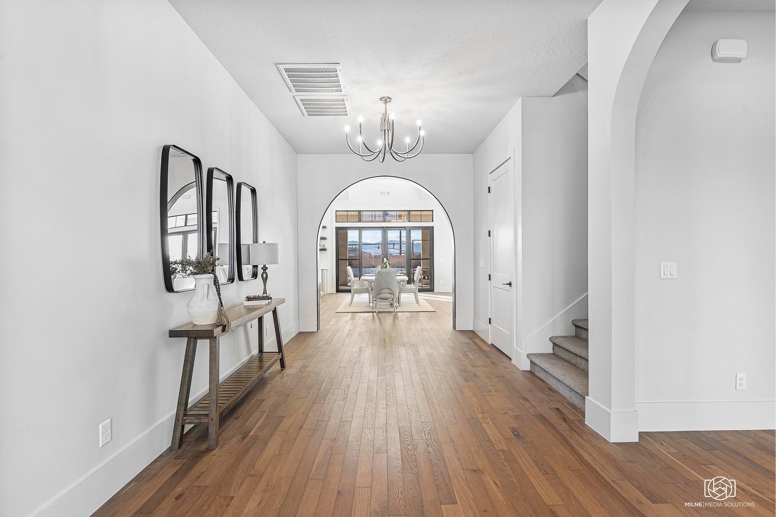 Foyer with hardwood / wood-style floors, arched walkways, and a chandelier