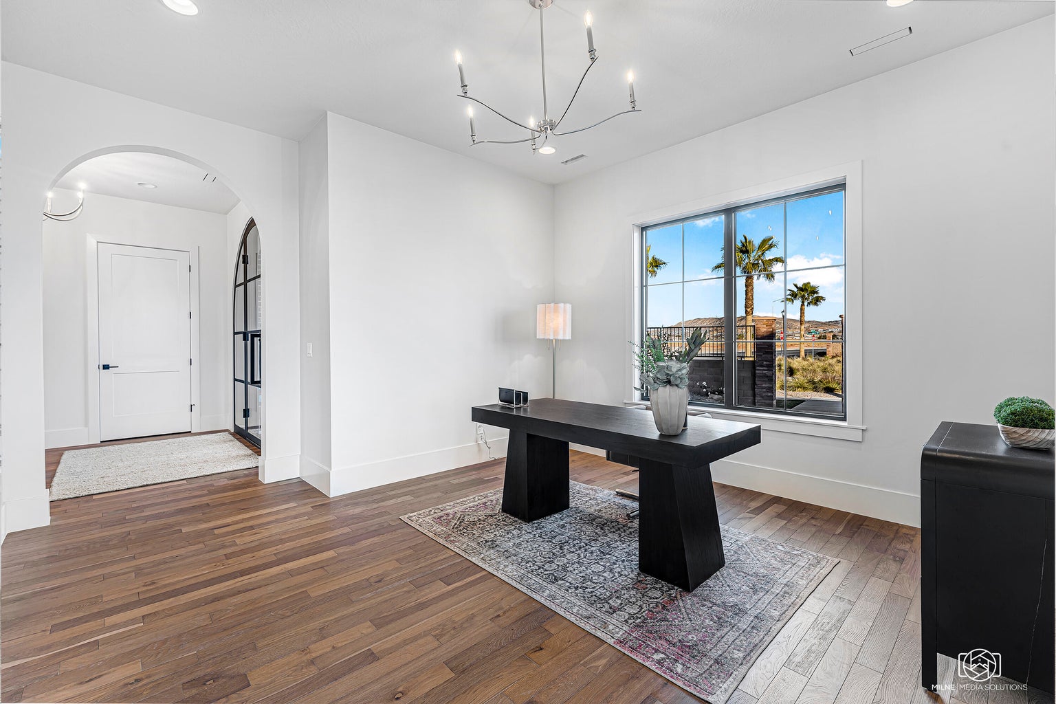 Office area featuring arched walkways, suspended lighting, and hardwood / wood-style floors