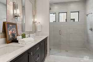 Full bath featuring double vanity, a stall shower, and tile walls