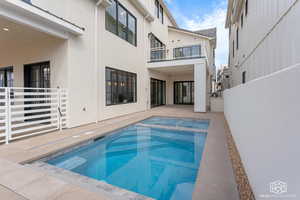 View of swimming pool featuring patio surround and a balcony