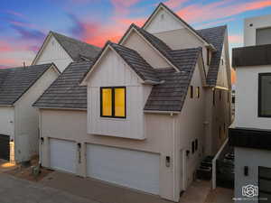 View of front of house featuring board and batten siding, concrete driveway, and stucco siding