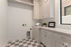 Laundry area with light floors, hookup for an electric dryer, washer hookup, and cabinet space