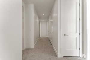 Corridor featuring recessed lighting and light colored carpet