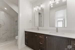 Bathroom with double vanity, a marble finish shower, and recessed lighting