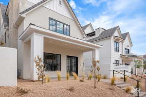 Modern inspired farmhouse with board and batten siding, covered porch, and stone siding