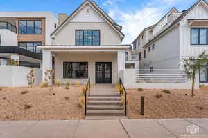 View of front facade with stucco siding, board and batten siding, french doors, and a porch