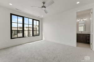 Unfurnished bedroom featuring light colored carpet, a ceiling fan, recessed lighting, and ensuite bath