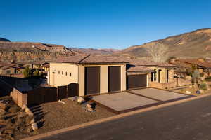 View of front of property with a mountain view, a gate, stucco siding, concrete driveway, and a garage