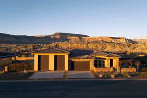 View of front of house featuring an attached garage, a mountain view, driveway, a tile roof, and stone siding