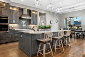 Kitchen featuring a kitchen breakfast bar, backsplash, light wood-style floors, and pendant lighting
