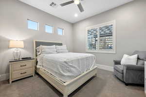 Bedroom with multiple windows, a ceiling fan, and dark carpet