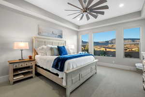 Bedroom featuring light carpet, a mountain view, a ceiling fan, a raised ceiling, and recessed lighting