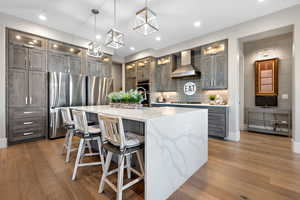 Kitchen with glass fronted cabinets, light wood-type flooring, stainless steel appliances, backsplash, and light stone counters