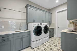 Laundry room featuring washing machine and clothes dryer, cabinet space, and light floors