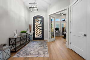 Entryway featuring light wood-style flooring, a chandelier, ceiling fan, and french doors