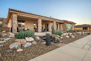 View of front facade featuring stucco siding, a patio, and stone siding