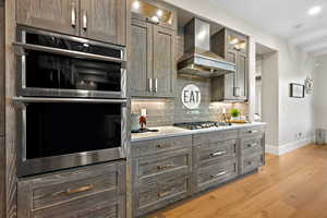 Kitchen with stainless steel appliances, light wood-style flooring, glass fronted cabinets, tasteful backsplash, and recessed lighting