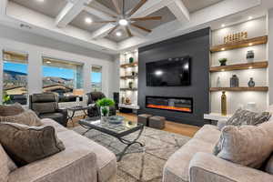 Living room with built in features, wood finished floors, a glass covered fireplace, coffered ceiling, and recessed lighting