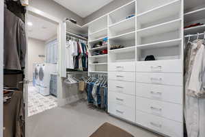 Walk in closet featuring light colored carpet and washing machine and clothes dryer