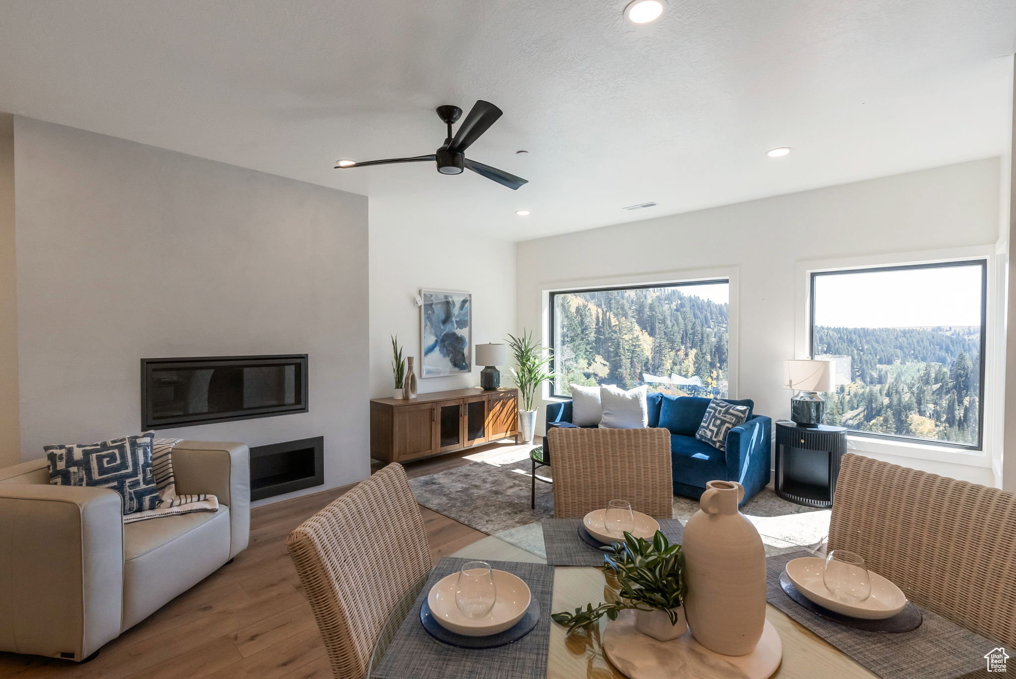 Dining room with wood finished floors, ceiling fan, a glass covered fireplace, and recessed lighting