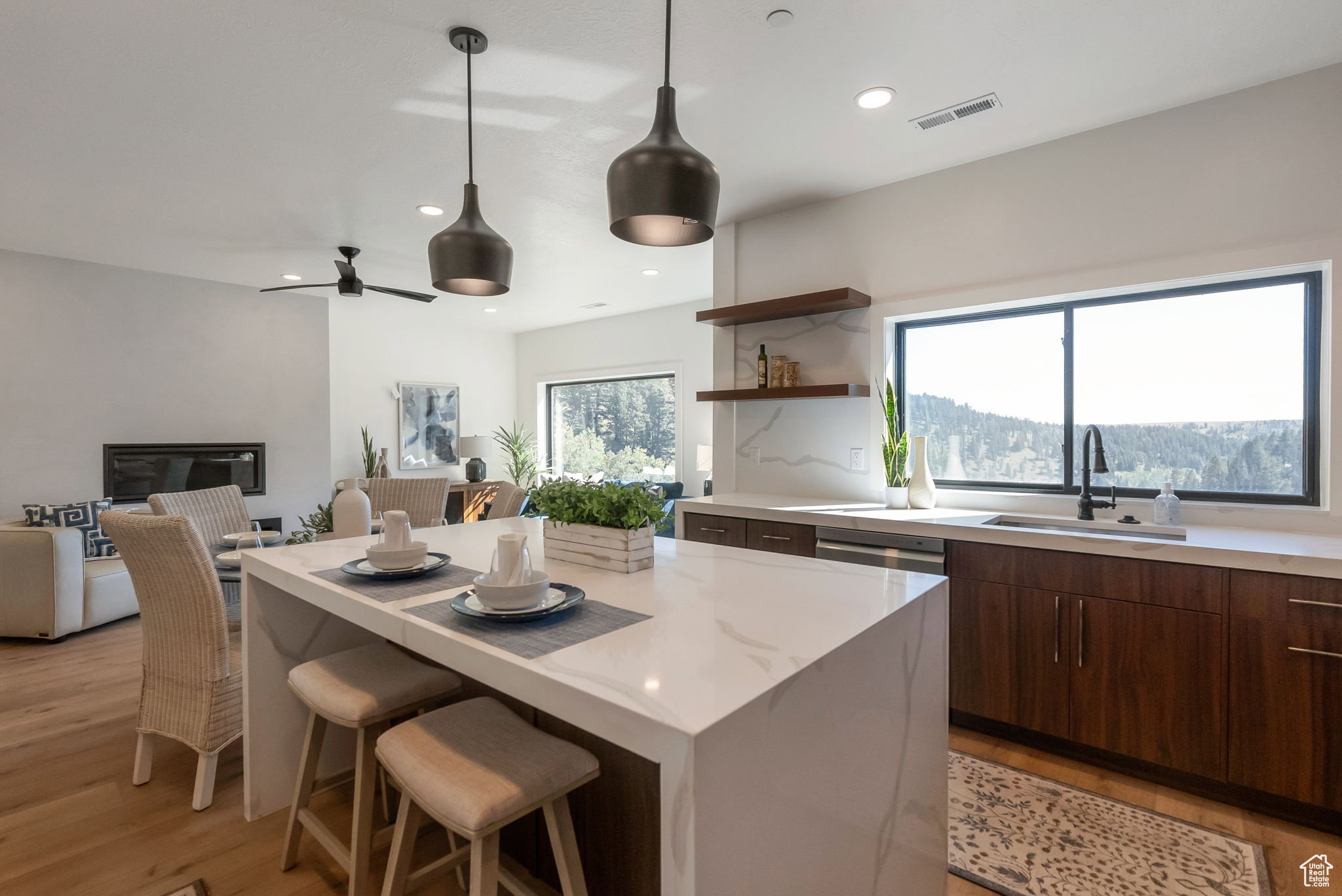 Kitchen featuring a breakfast bar area, open floor plan, light stone counters, open shelves, and dark wood finish cabinets