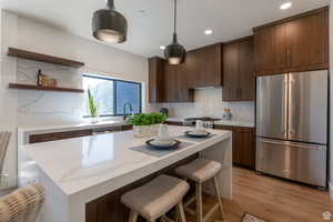 Kitchen with stainless steel appliances, dark wood finish cabinets, light wood-style flooring, and modern cabinets