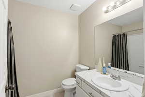 Full bathroom with vanity, curtained shower, and a textured ceiling